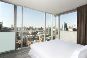 a bedroom with a white bed and large windows at Hotel on Rivington in New York