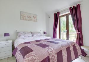 a bedroom with a purple and white bed and a window at Hexden Lea in Rolvenden