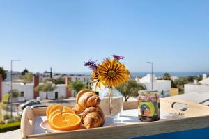- un plateau avec des oranges, des croissants et un vase avec des fleurs dans l'établissement Villa Roxana, à Porches