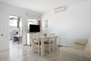 ein Wohnzimmer mit einem Tisch, Stühlen und einem TV in der Unterkunft Casa Josisa - Solo Familias in Conil de la Frontera