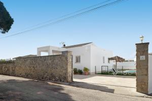 ein weißes Haus mit einer Steinmauer in der Unterkunft Casa Josisa - Solo Familias in Conil de la Frontera