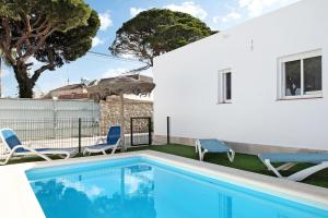 a swimming pool with two chairs and a house at Casa Josisa - Solo Familias in Conil de la Frontera