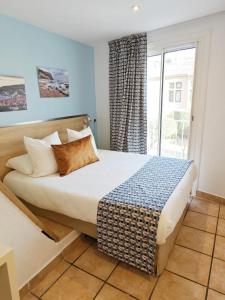 a bedroom with a large bed with a window at HOTEL DES CALANQUES in Cassis