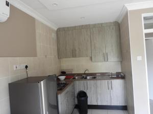 a small kitchen with a sink and a refrigerator at 2 Bed Apt with en-suite and kitchenette - 2066 in Harare