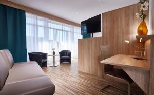 un soggiorno con divano e scrivania con TV di Hotel zum Stern a Schweich