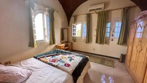 a bedroom with a bed in a room with windows at Pharaonicas in Al Aqālitah