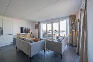 a living room with two couches and a large window at Meerzicht 24 - Luxury family accommodation with beautiful lake side view in Uitgeest