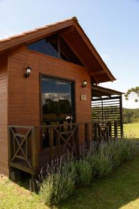 uma cabina de madeira com uma grande janela e um alpendre em Pousada Querência Tarumã em São Joaquim