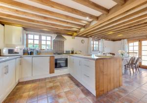 a large kitchen with white cabinets and a table at Iden Green Farm Stables in Benenden