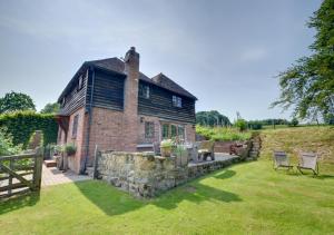 an old brick house with a stone wall in a yard at Iden Green Farm Stables in Benenden