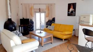a living room with a yellow couch and a table at La Forgeolie in Causses-et-Veyran