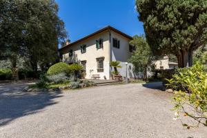 una gran casa blanca con árboles y una entrada de grava en Fattoria la Gigliola - Villa Milani, en Montespertoli