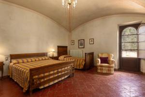 1 dormitorio con 2 camas, silla y lámpara de araña en Fattoria la Gigliola - Villa Milani, en Montespertoli