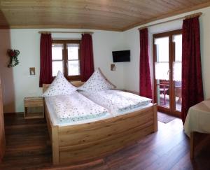 a bedroom with a wooden bed in a room with windows at Pension Staufenhof in Inzell