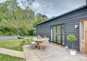 a patio with a table and chairs in a yard at Little Orchard in Sedlescombe