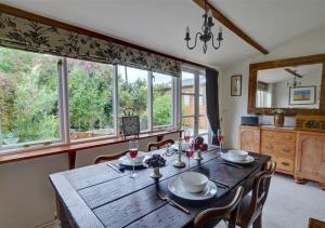een eetkamer met een houten tafel en een aantal ramen bij Marigold Cottage in Rolvenden
