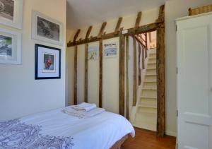 a bedroom with a bed and a stair case at Marigold Cottage in Rolvenden