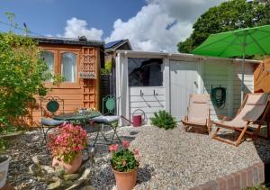 a garden with a table and chairs and a shed at Marigold Cottage in Rolvenden