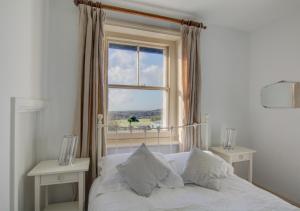 a bedroom with a white bed and a window at Lower Coastguard Cottage in Hastings