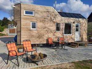 a tiny house with chairs and a table in front of it at Tiny Haus am Motzener See in Motzen