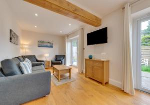 a living room with a couch and a tv at Maple Cottage in Woodchurch