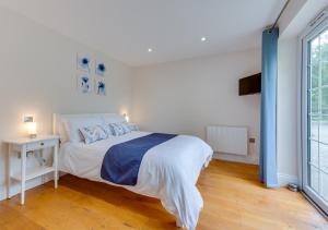 a white bedroom with a bed and a window at Maple Cottage in Woodchurch