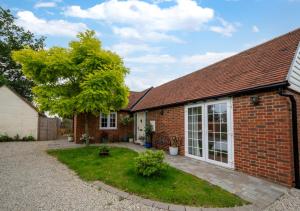 a brick house with a tree in the yard at Maple Cottage in Woodchurch