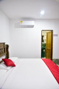 a white bed with red pillows in a room at Hotel Beijing Caucasia in Caucasia