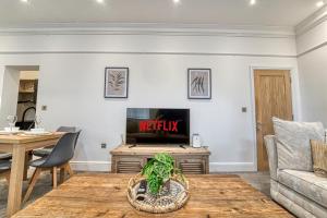 a living room with a table and a tv at Guest Homes - The Bell Apartment in Stourbridge