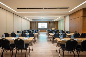 une salle de conférence avec des tables et des chaises et un écran de projection dans l'établissement Urcove by HYATT Shanghai Wujiaochang, à Shanghai