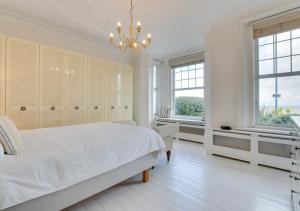 a white bedroom with a bed and a chandelier at Number 46 in Whitstable