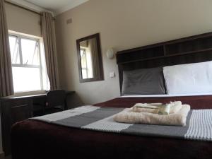 a bedroom with a bed with two towels on it at 2 bedroomed apartment with en-suite and kitchenette - 2070 in Harare