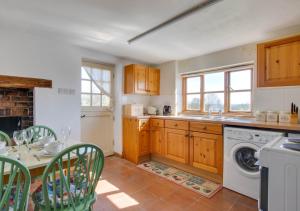 a kitchen with wooden cabinets and a washer and dryer at Orchard Cottage in Sutton Valence