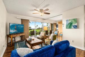 a living room with a blue couch and a tv at Keauhou Akahi 302 in Kailua-Kona