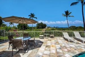 a patio with a table and chairs and an umbrella at Keauhou Akahi 302 in Kailua-Kona