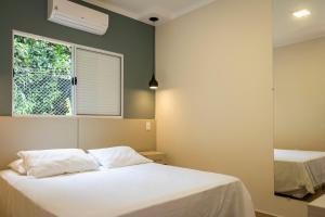 1 dormitorio con cama blanca y ventana en Pousada Terra Rossa, en São José do Rio Pardo
