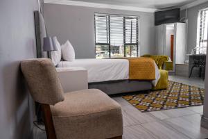 1 dormitorio con 1 cama grande y 1 silla en Greenlake Guesthouse en Maseru