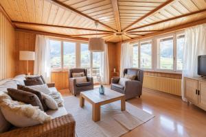 a living room with a couch and chairs and a tv at The Eiger Express Apartment - GRINDELHOMES in Grindelwald