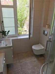 La salle de bains est pourvue de toilettes, d'un lavabo et d'une fenêtre. dans l'établissement Najs Apartamenty z parkingiem, à Sopot