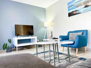 a living room with a tv and a blue chair at Chic Modern House on Neasden - 2085 in Bulawayo