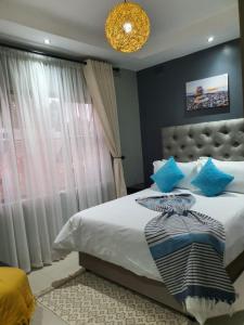 um quarto com uma cama com almofadas azuis e uma janela em Posh 3 bedroomed guesthouse in Hillside with pool - 2039 em Bulawayo