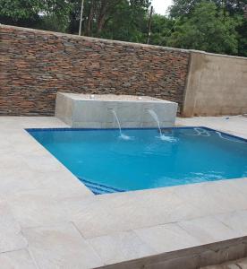 una piscina con una fuente en una pared de ladrillo en Posh 3 bedroomed guesthouse in Hillside with pool - 2039, en Bulawayo