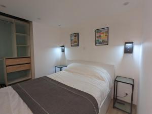 een slaapkamer met een bed en twee lampen aan de muur bij A deux pas mer et falaises in Mers-les-Bains