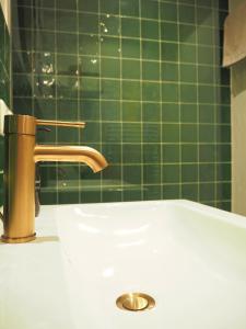 a bathroom sink with a gold faucet and green tiles at Das Altschwabing - Munich Boutique Hotel in Munich +12 photos
