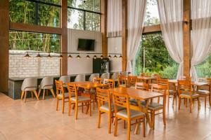 un restaurante con mesas y sillas de madera y ventanas en Pousada Terra Rossa, en São José do Rio Pardo