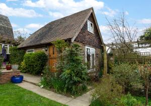 una pequeña casa de ladrillo con puerta de madera en Rose Cottage, en Hawkhurst