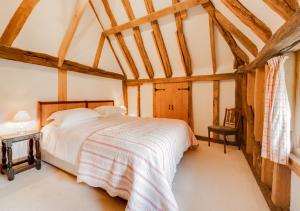 a bedroom with a bed in a room with wooden ceilings at Strawberry Hole Barn in Northiam