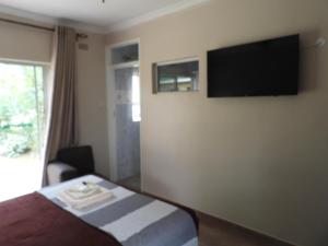 a hotel room with a bed and a flat screen tv at 2 bedroomed apartment with en-suite and kitchenette - 2069 in Harare