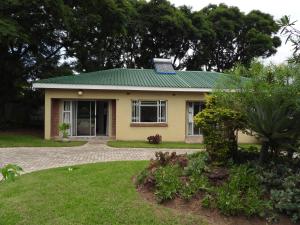 a small yellow house with a green roof at 2 bedroomed apartment with en-suite and kitchenette - 2069 in Harare