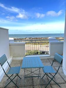 スラック・シュル・メールにあるAppartement vue merのビーチ付きのバルコニー(青い椅子2脚、テーブル付)